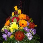 Seasonal flowers including Gerberas and Roses in a ceramic pot arrangement
